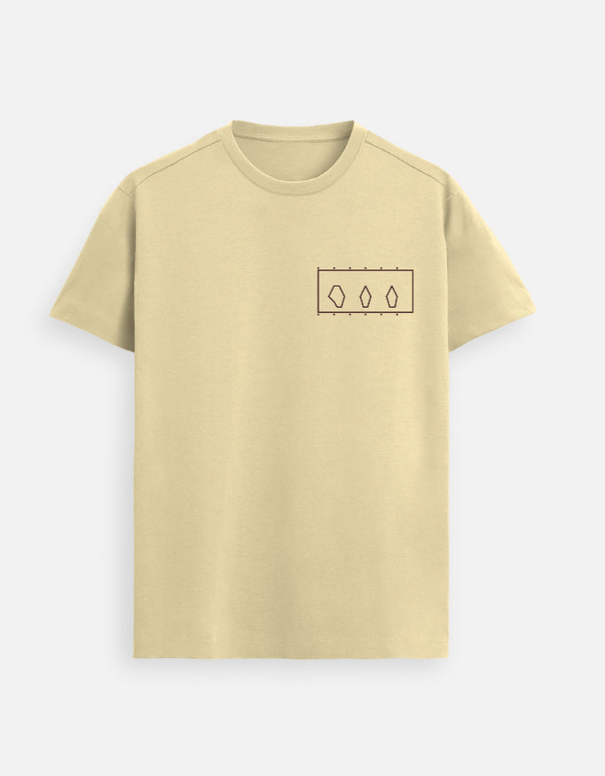 Woman standing inside a modern art museum wearing a Beige Supima cotton T-shirt by Lilak, featuring a minimal geometric design on the left chest